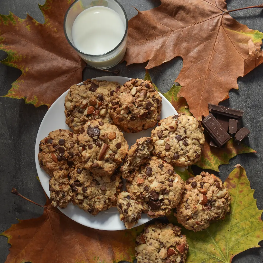 Cookies Maison Cookie décorés pour l'automne, entourés de feuilles colorées.